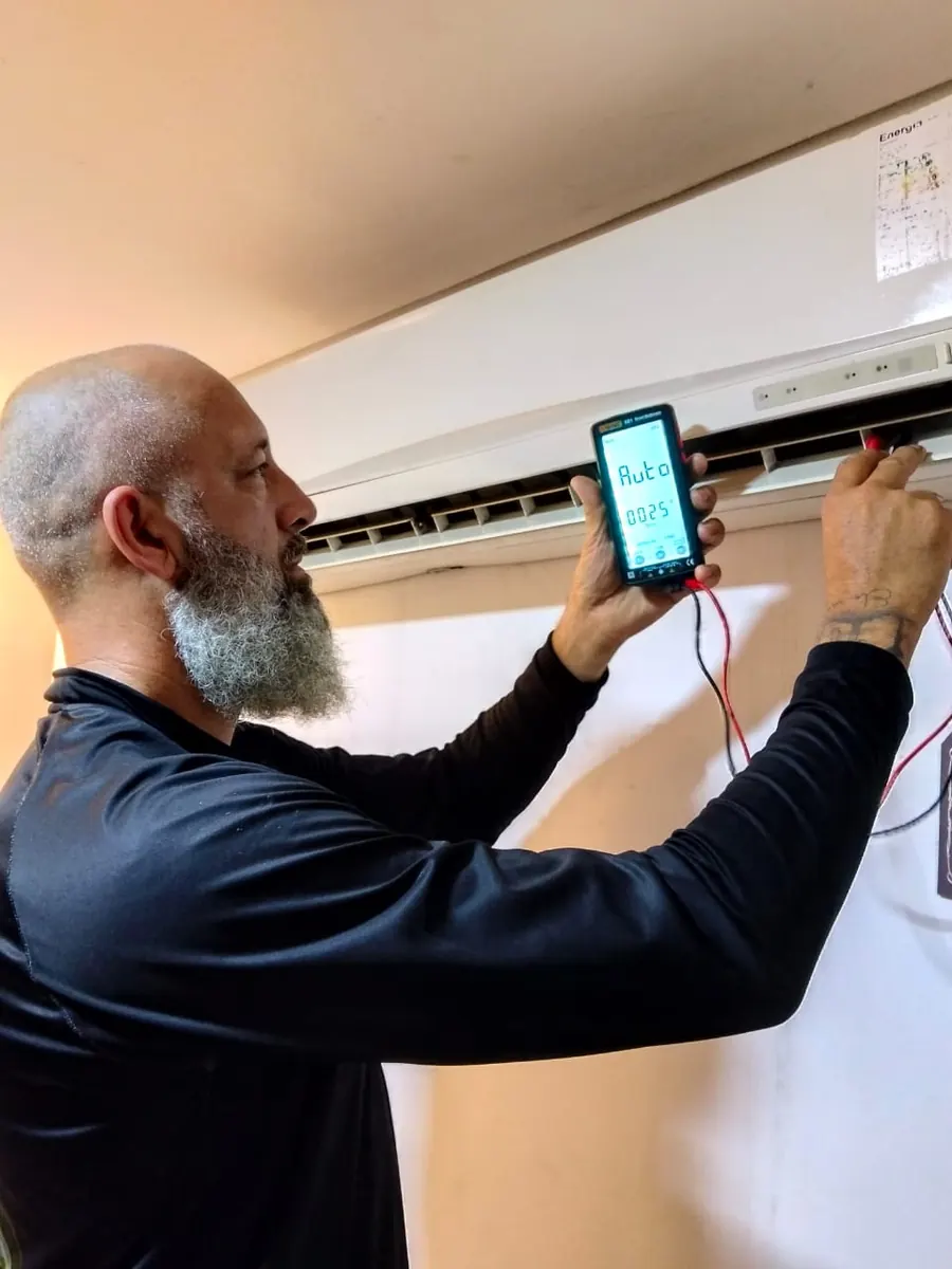 Técnico da Yahweh Refrigeração medindo com multímetro um ar condicionado split